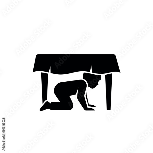 Child hiding under a table during an earthquake drill.