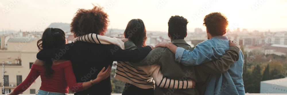 Fototapeta premium Guys and girls at the party, looking at the beautiful views and talking standing on the terrace, friendly party holiday at sunset. Panoramic
