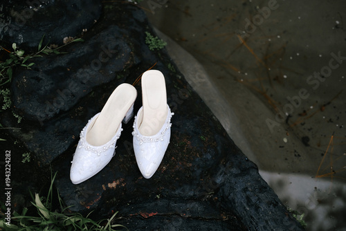 White Bridal Shoes Placed on Natural Stone Surface