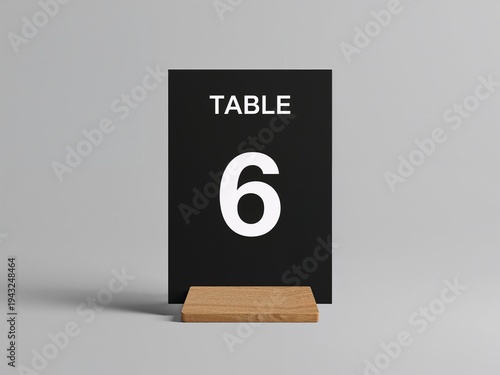 Black table number sign with number six on a wooden stand. Minimal signboard isolated on a clean background for restaurant or event seating.