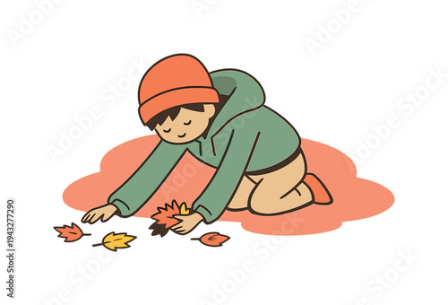 Child in beanie and hoodie collecting colorful autumn leaves on the ground