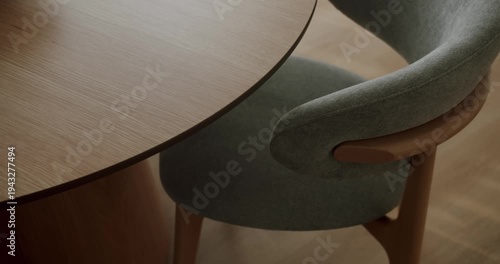 High-angle view showing an elegant modern dining room setting with a stylish gray upholstered chair next to a round wooden table. Highlighting contemporary interior design and furniture craftsmanship