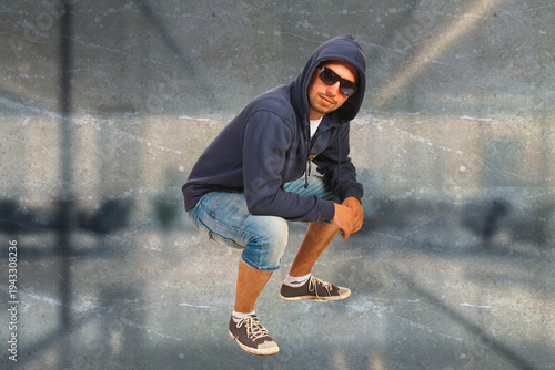 Young man crouches stylishly in urban setting