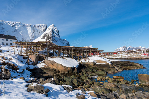 Bilde på lerret Snowy coastal landscape with wooden fish drying racks and mountains in Lofoten,