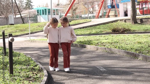 two little twin girls walking in the park in spring