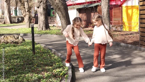 two little twin girls walking in the park in spring