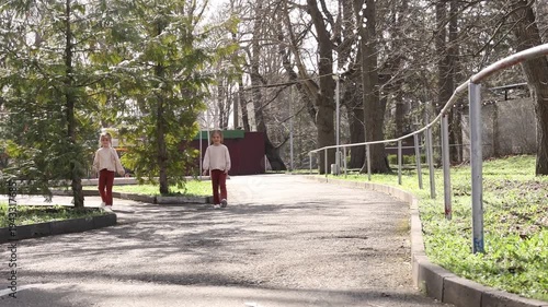 two little twin girls walking in the park in spring