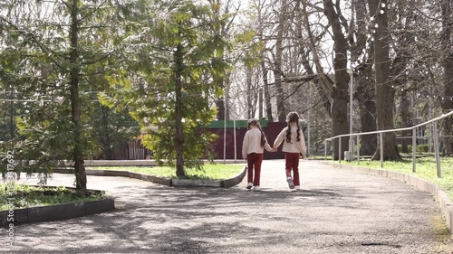 two little twin girls walking in the park in spring