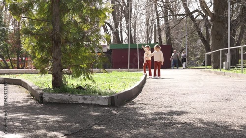 two little twin girls walking in the park in spring