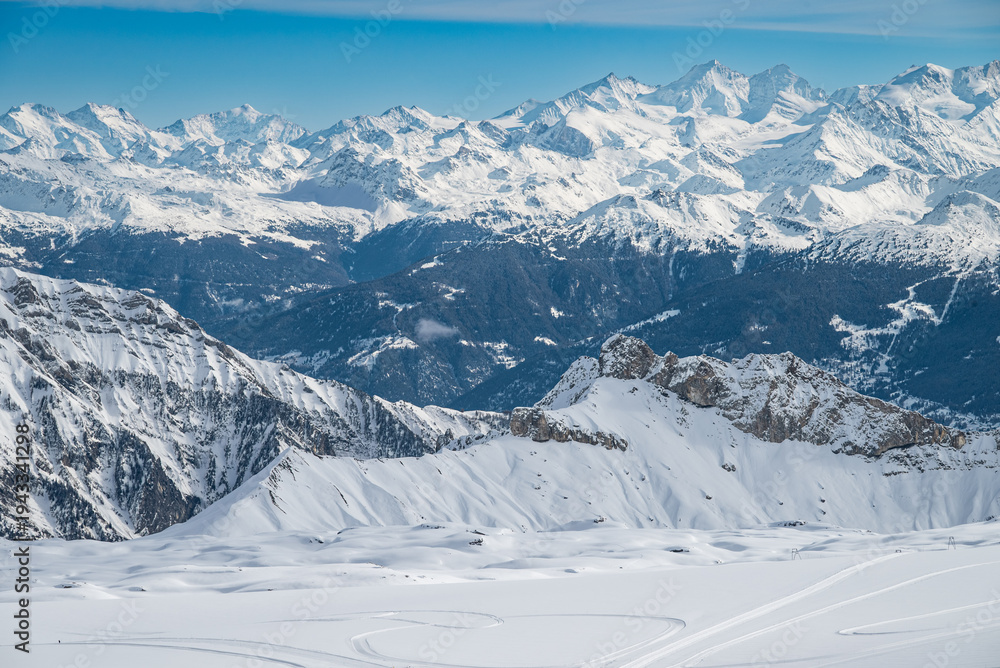 Fototapeta premium Panoramic view of snowy mountain range under clear blue sky