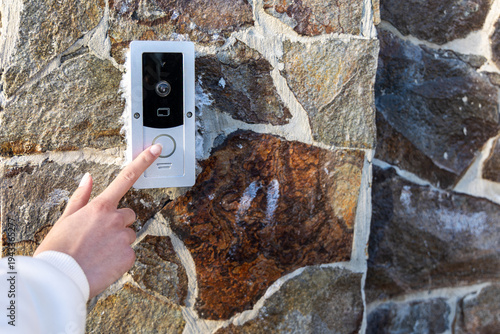 Photography Hand Pressing Video Doorbell on Stone Wall