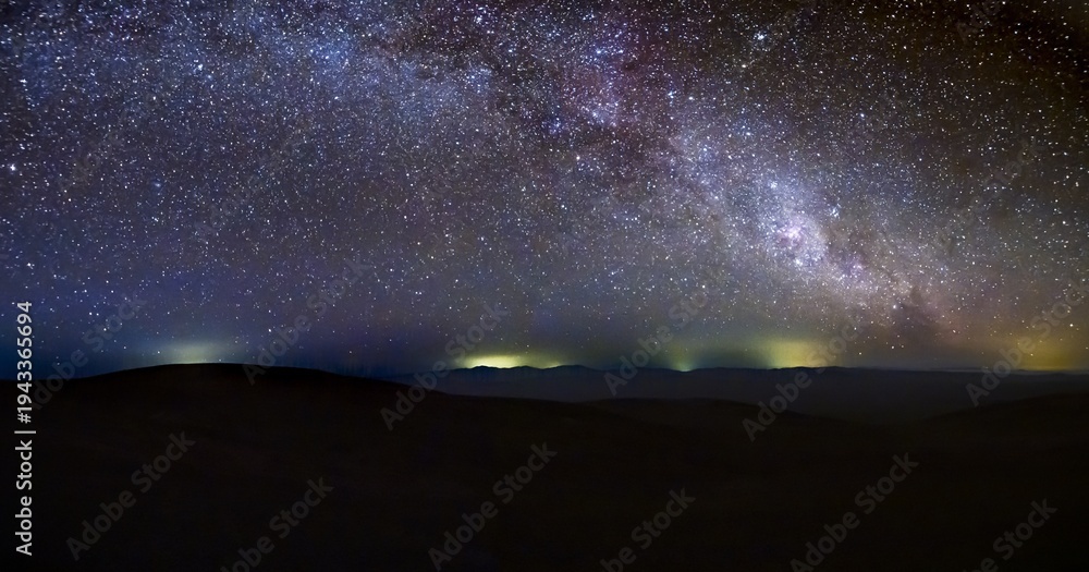 Fototapeta premium Panoramic nightscape of Atacama Desert under Milky Way galaxy. Breathtaking panoramic view of the Atacama Desert night sky, showcasing the light coming from mining activities and mountain silhouettes