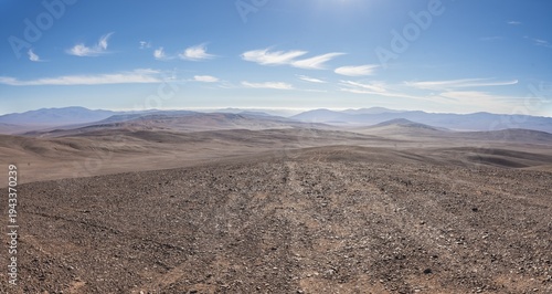Panoramic view of Atacama Desert, Vaca Muerta strewnfield, Chile. Vast arid landscape with rocky terrain and distant mountains under a clear blue sky in the Atacama Desert, Chile.