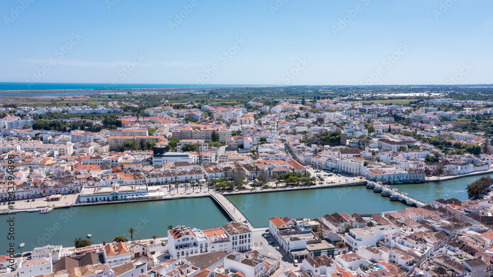 Fototapeta premium Tavira in Algarve is seen from above with traditional buildings lined along the Gilao river. The coastline and countryside can be observed in the distance