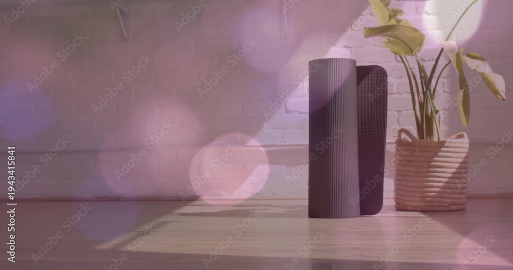 Fototapeta premium Standing dark rolled yoga mat beside basket planter holding leafy plant on wood floor, copy space
