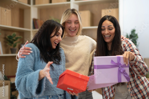 Three happy friends opening surprise present boxes