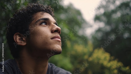 Contemplative young man looking up in the rain