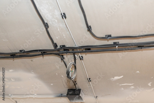 open wiring electrical wires grouped on the ceiling of a room.