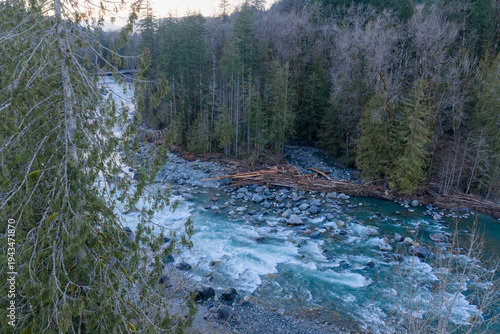 Mountain River Rapids Flowing Through Evergreen Forest and Rocky Shoreline in BC, Canada