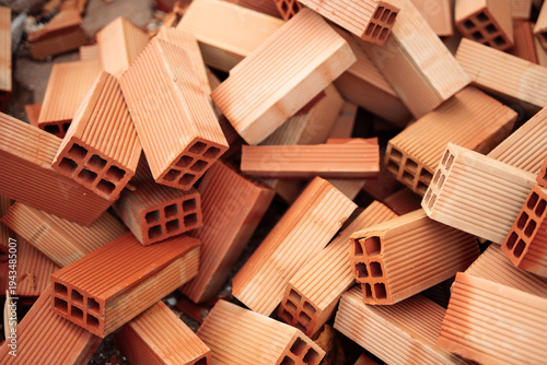 Close up of stacked hollow red clay bricks as construction material background, ceramic blocks for masonry, housing development, renovation, architecture, infrastructure, industrial building concept