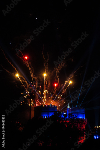 Fireworks over a brightly lit castle at night in dramatic photography on dark background, concept of celebration and festivity