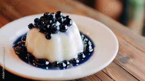 Delicious creamy dessert topped with fresh, glistening blueberries and sweet syrup on an elegant white plate.