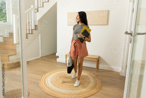 Billede på lærred Indian woman in early 20s walking in foyer wearing white sneakers holding two no