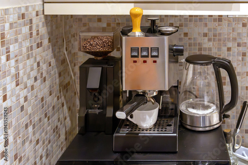 Domestic coffee station featuring a chrome espresso maker a bean grinder and a glass electric kettle