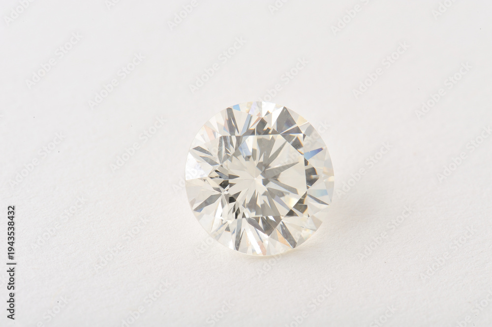 Fototapeta premium A sparkling diamond rests on a plain white surface, catching light with its brilliant facets.