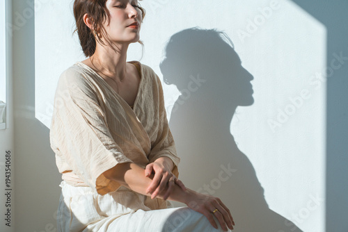 фотографія A woman by the window in the setting sun (model, fashion, light, shadow)