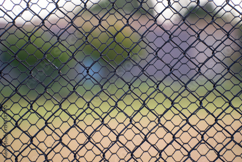 close up of looking through two chain link fences of different sized shapes or holes geometrical shapes inside each other two layers of fencing fir protection security and anti theft  