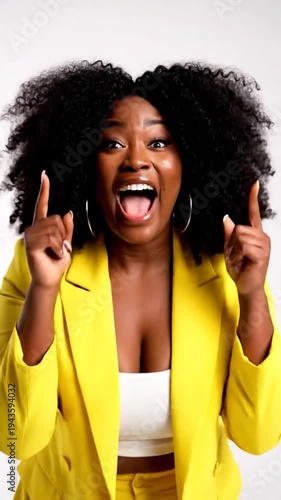 A joyful person with curly hair laughs heartily in a bright yellow suit