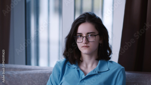 Free Download Young Woman Wearing Glasses Sitting on Couch Indoors, a serious young business woman - GFXLoad