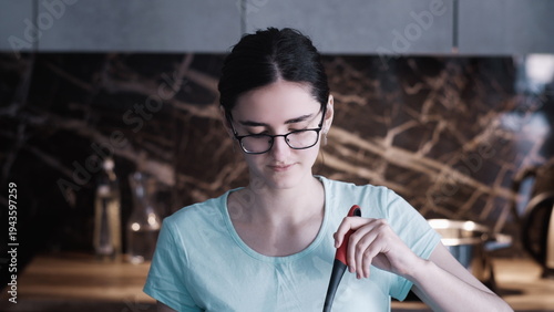Obraz na plátně Young Woman Cooking in Modern Kitchen with Marble Backsplash