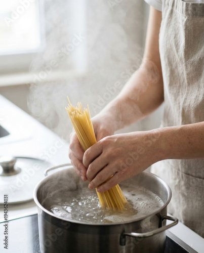 Person in Linen Apron Lowering Spaghetti into Stainless Steel Pot