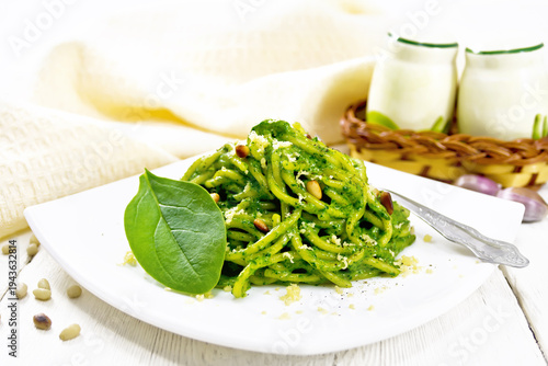 Spaghetti with spinach and pine nuts in plate on board