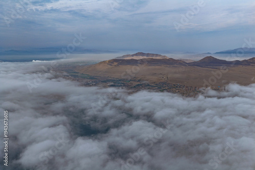 Aerial view of city and desert peaks with low clouds at dawn