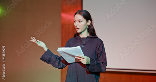 Fotografie Indian young adult gen z female lady standing wear outfit dress hold script paper do play scene practice indoor hall stage
