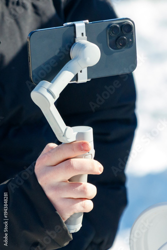Canvas Print Close-up of person holding phone on stabilizer in snow