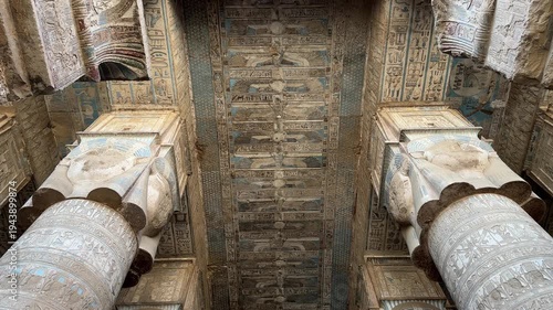 Cinematic low angle shot of the grand Hathoric columns and the intricately decorated astronomical ceiling with ancient Egyptian hieroglyphs inside the Temple of Hathor in Dendera
