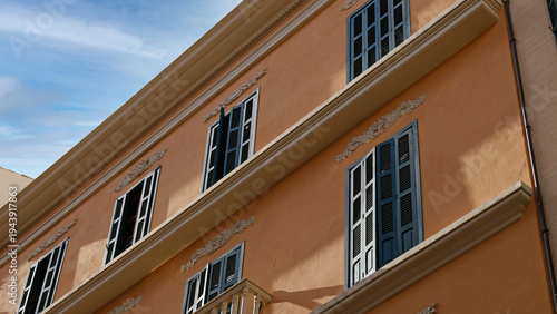 Mediterranean house with Neoclassical stucco detailing and tall shuttered windows in soft daylight. For lifestyle, travel and property campaigns.