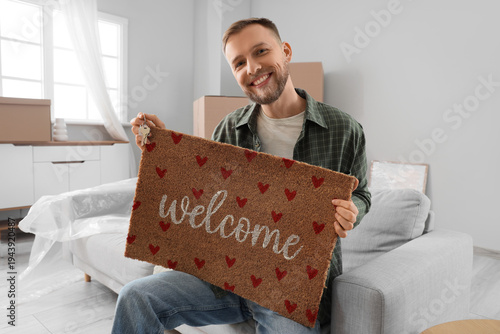 Young man with doormat sitt...