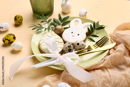 Beautiful table setting with sweet cookies, leaves and Easter eggs on beige background, closeup