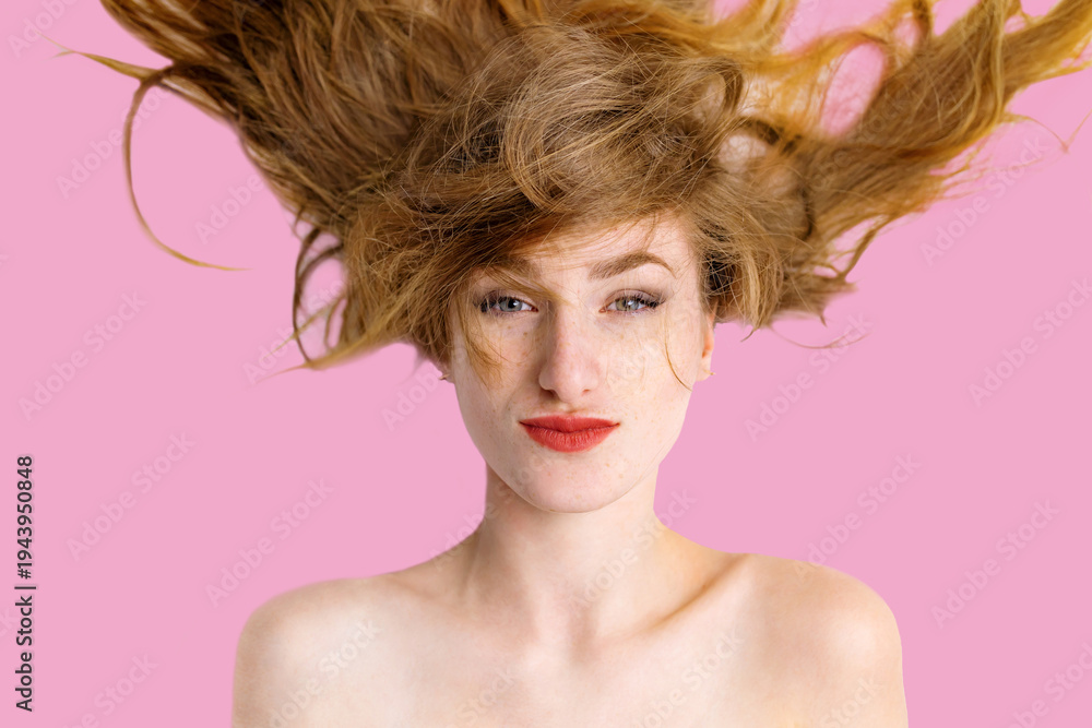 Naklejka premium a joyful young woman with strawberry blonde hair lying on a white surface. She is captured in a moment of genuine laughter, with her eyes squinted shut and a wide, bright smile revealing white teeth. 