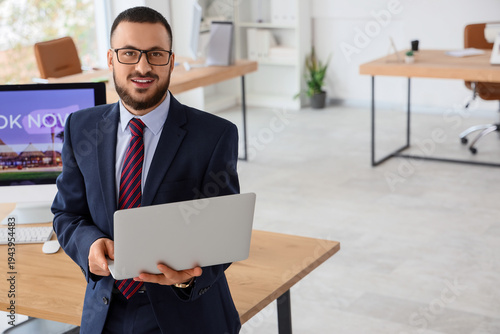 Young businessman using laptop to search for tickets online in office
