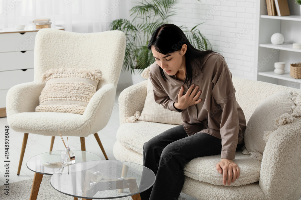 Fototapeta premium Young worried woman having panic attack on sofa at home