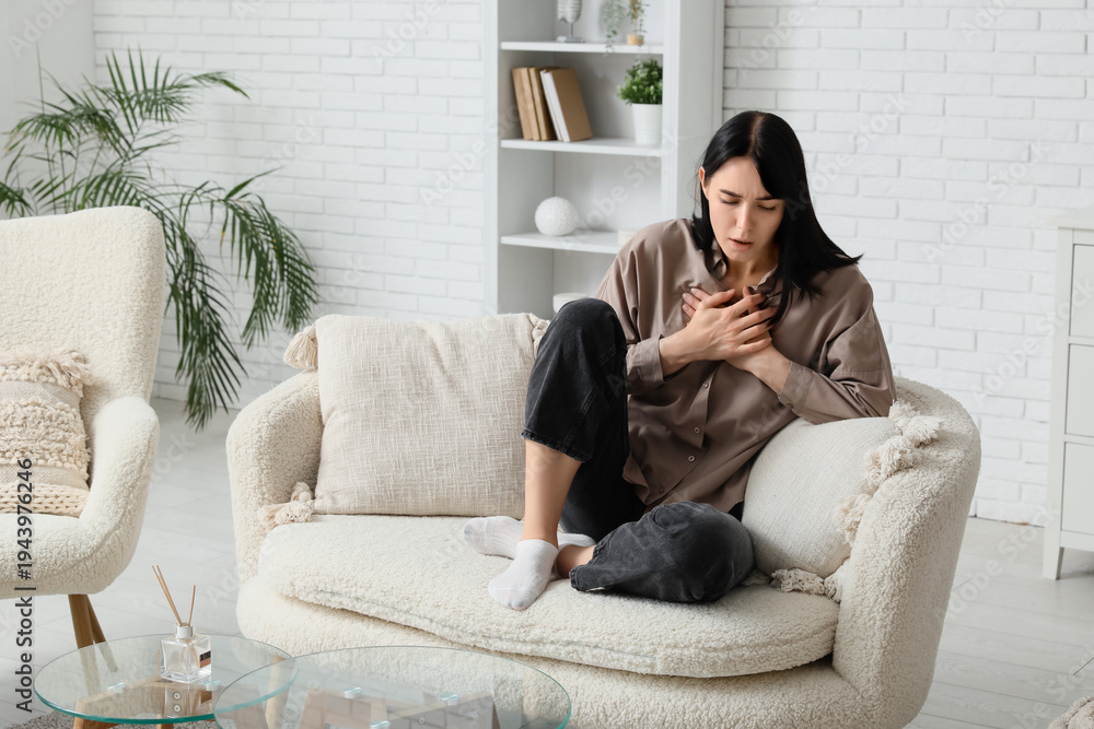 Obraz premium Young worried woman having panic attack on sofa at home