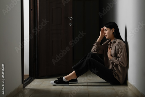 Young woman having panic attack on floor in hallway at home