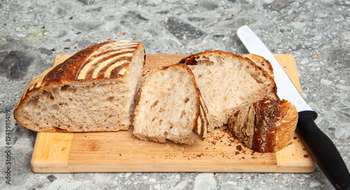 Slices of bread with a long knife on a wooden cutting board.