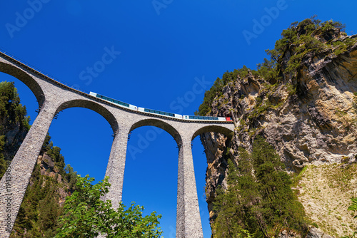 Iconic Landwasser viaduct conveys engineering grandeur, travel adventure, and harmony between railway architecture and mountain nature.